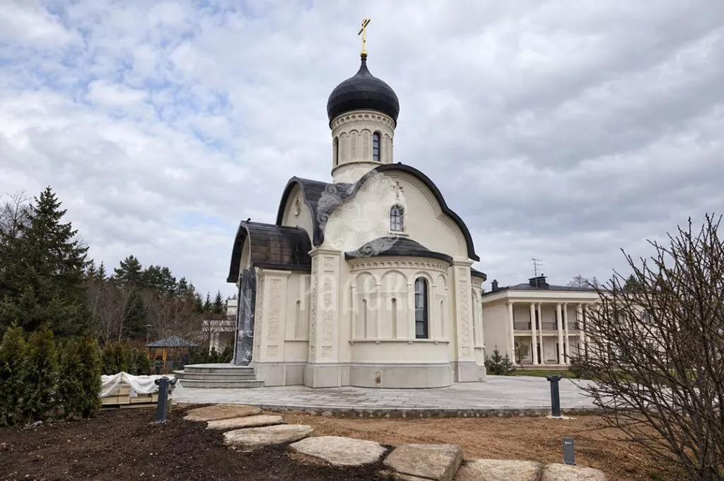 General view of the church with a light relief facade, dark roof, and onion dome.