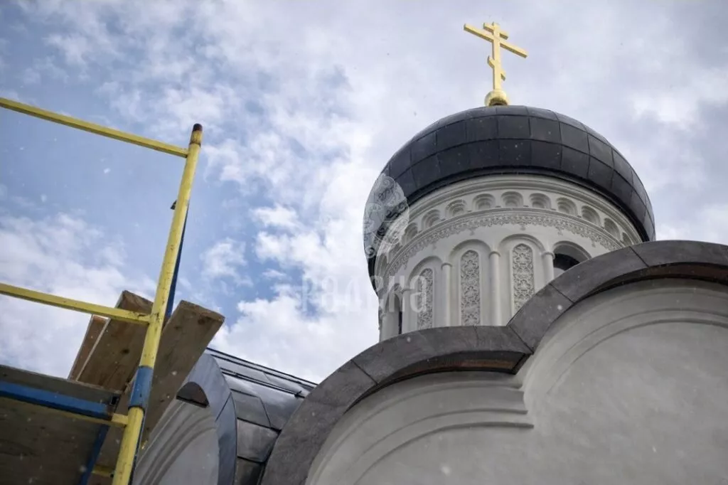 Dome with a cross above the shaped finishes of the church facade, view from the scaffolding.