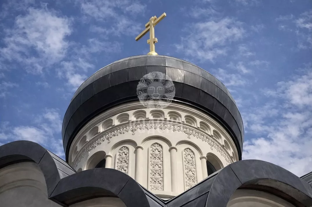 Купол с золотым крестом и резной барабан храма над округлыми линиями кровли.