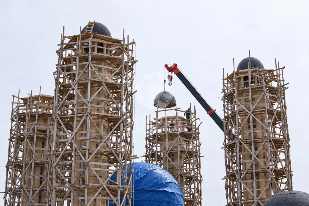 Подъём купольного завершения минарета краном на строительстве мечети в Грозном.