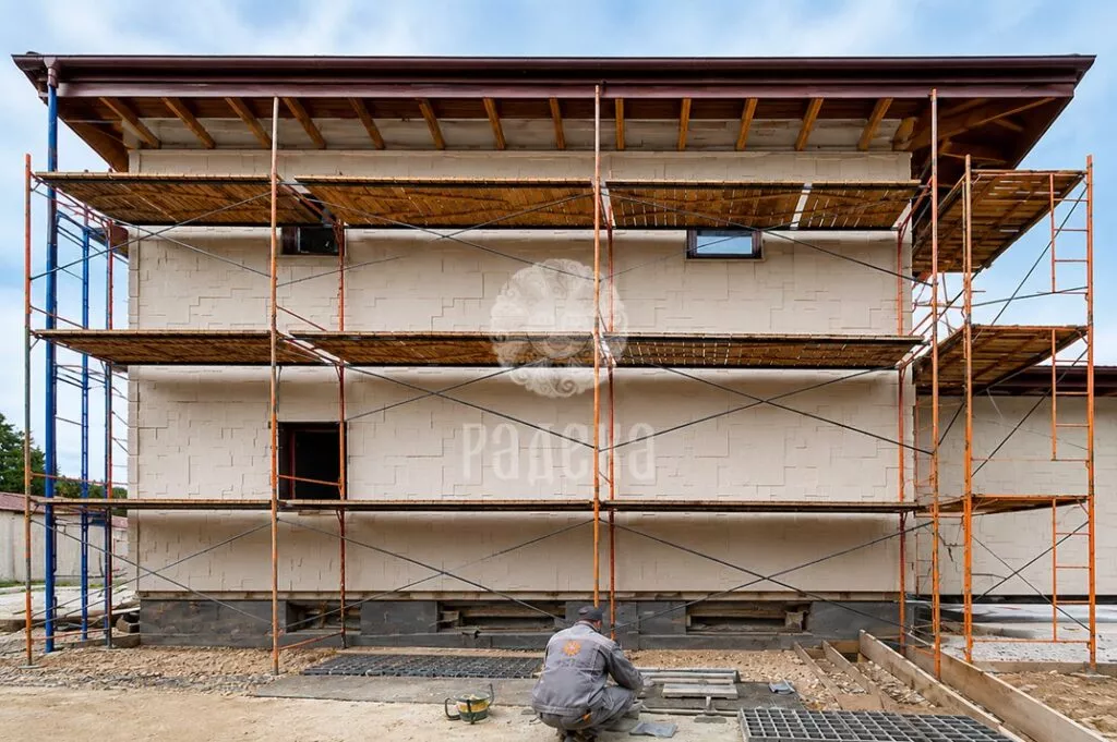 Facade finishing with natural stone in Barvikha during work from scaffolding.