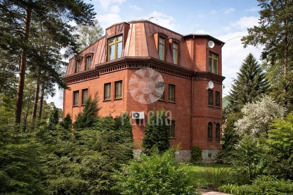 Brick private house with a copper mansard roof among trees