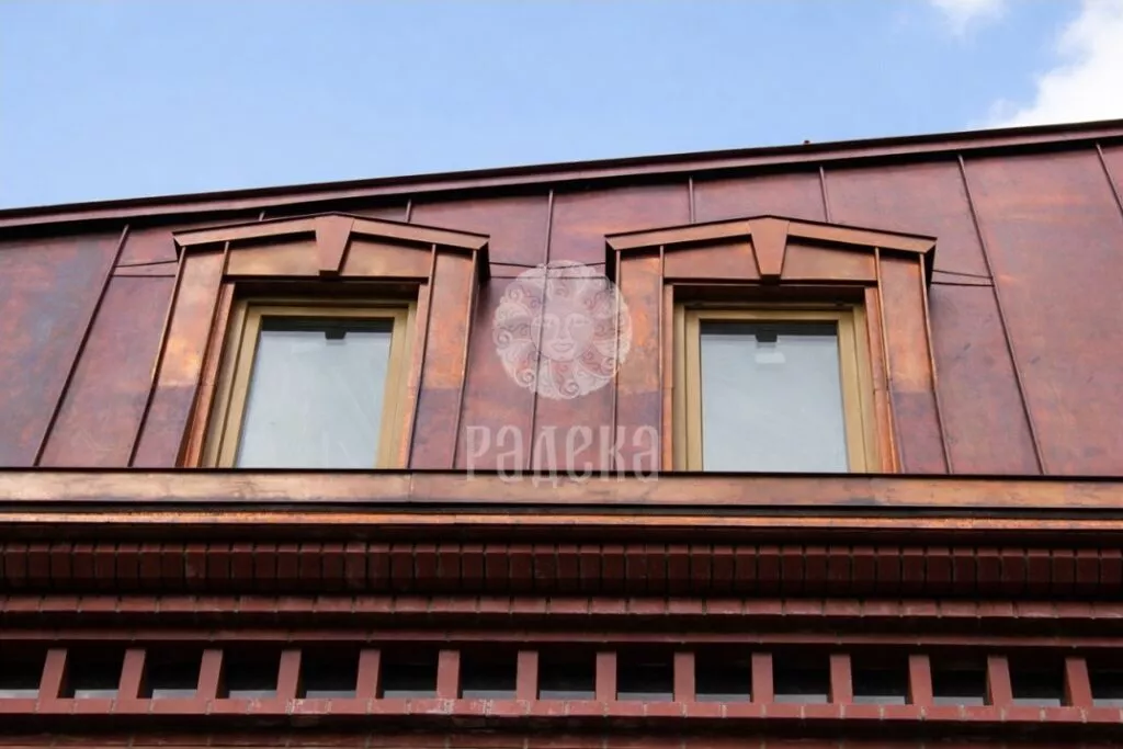 Front view of two dormer windows in a copper mansard roof