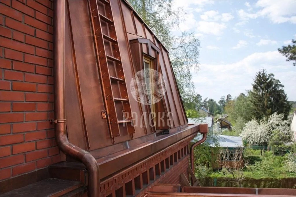 Roof ladder on a copper roof slope beside a copper downpipe