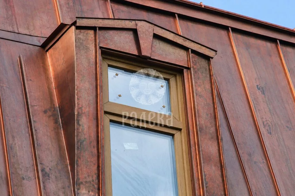Narrow dormer window with copper-clad reveals and decorative trim above the opening