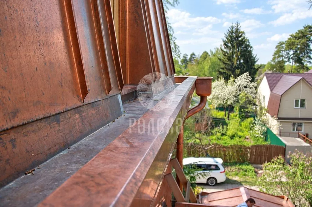 Copper gutter along the base of the mansard roof slope, with a hopper head at the end
