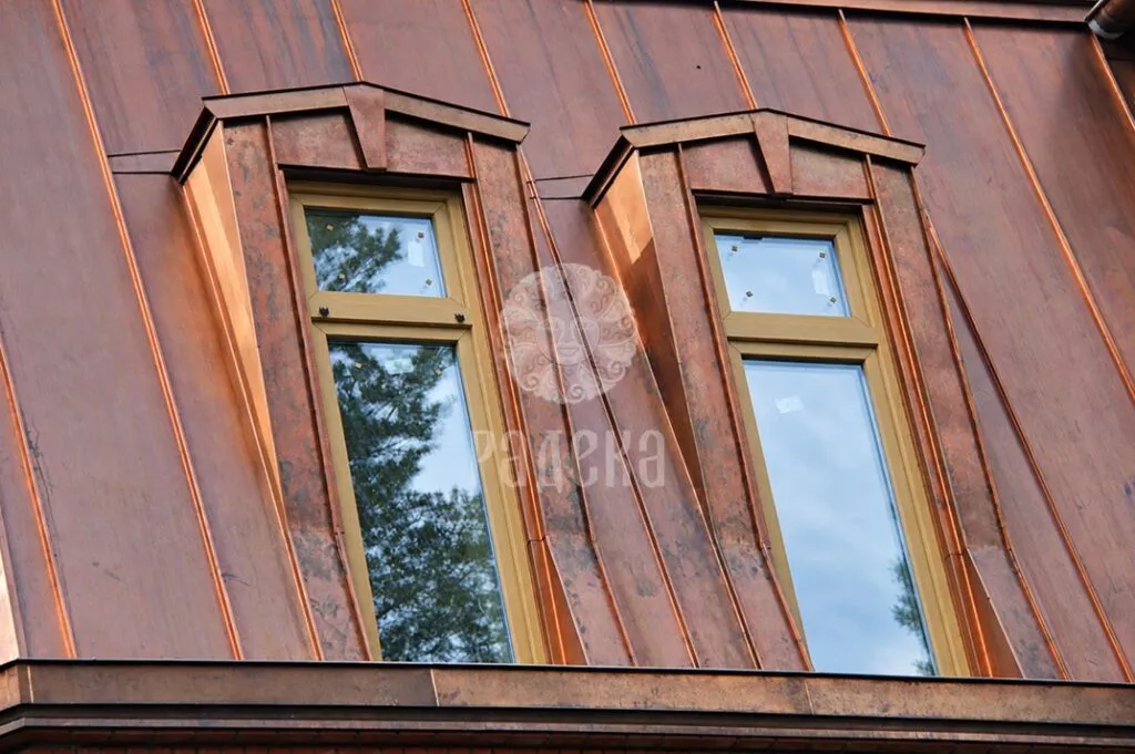 Two dormer windows with shaped copper framing on the standing seam roof