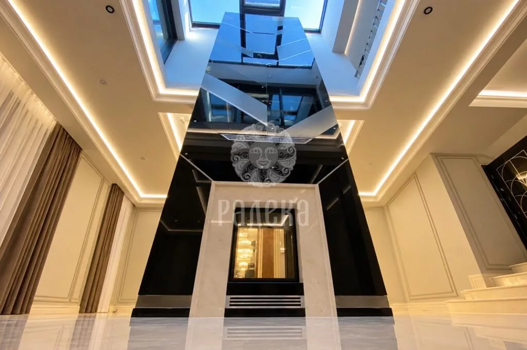Seven-meter-tall, double-sided fireplace beneath a skylight, with a chandelier visible through the see-through firebox.