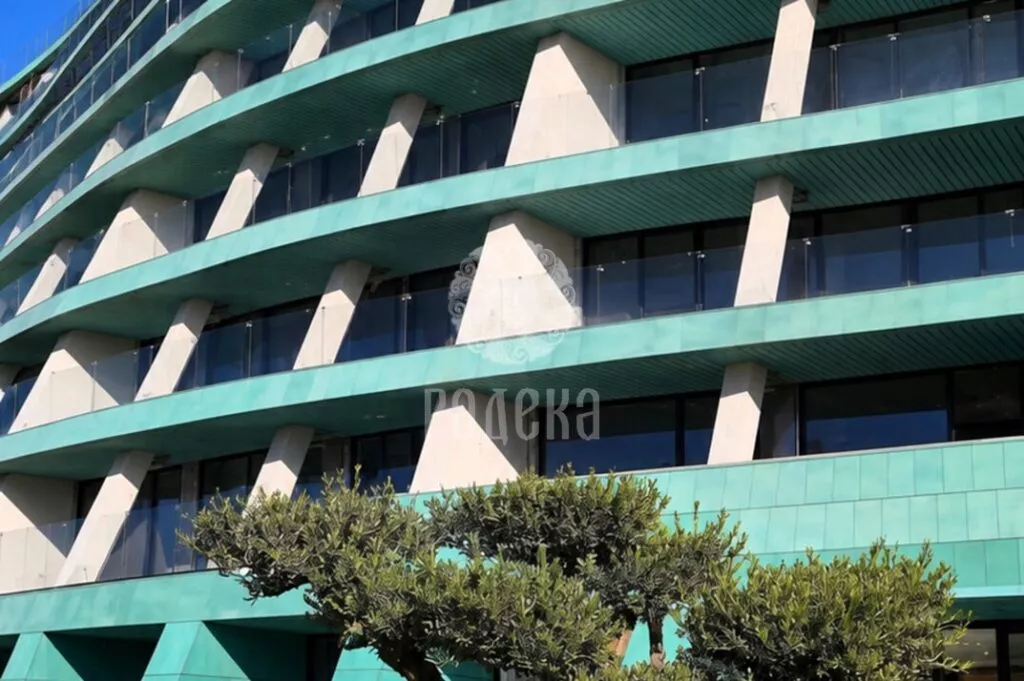 Copper belts and soffits of the Reef Residence balconies above an olive tree in the courtyard.