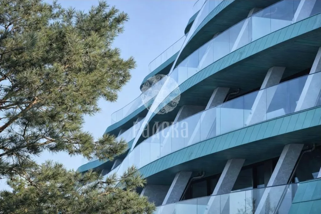Balconies of Reef Residence with copper belts, soffits, and glass railings next to a pine tree.