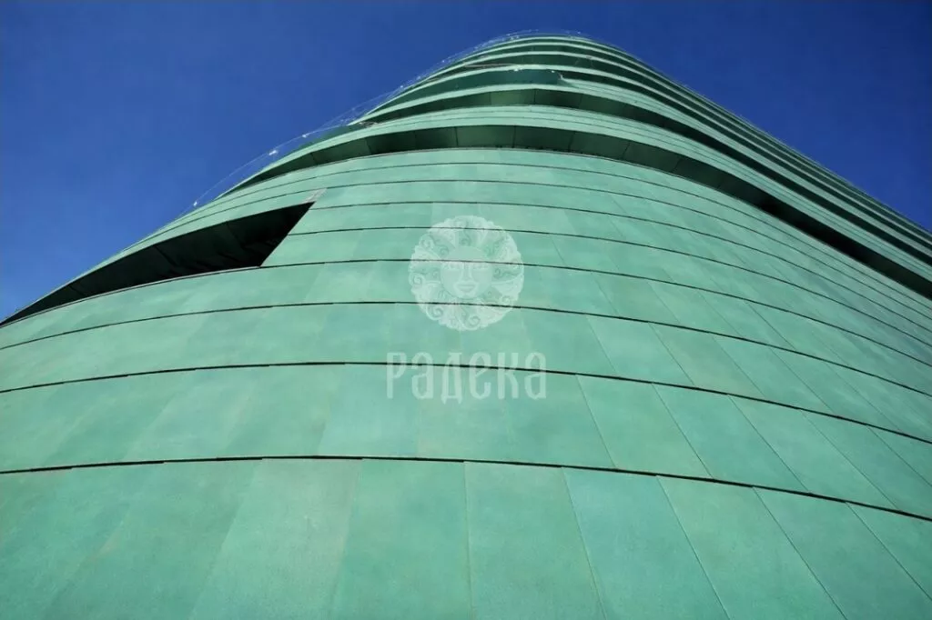 View from below of the rounded copper facade of Reef Residence and the upward lines of the balconies.