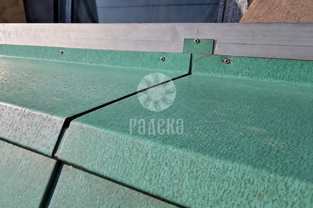 Joint of bent elements made of patinated copper with flanging and fastening on the Reef Residence facade.