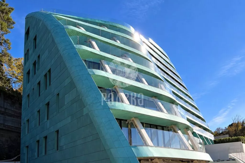 Rounded end of Reef Residence with copper cladding transitioning into horizontal balcony belts.